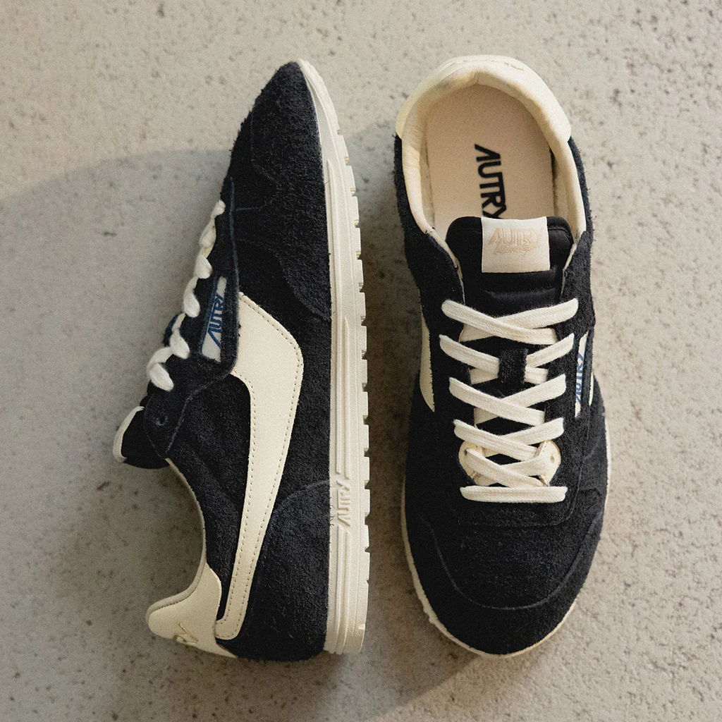 Black and white sneakers with laces on a textured surface.