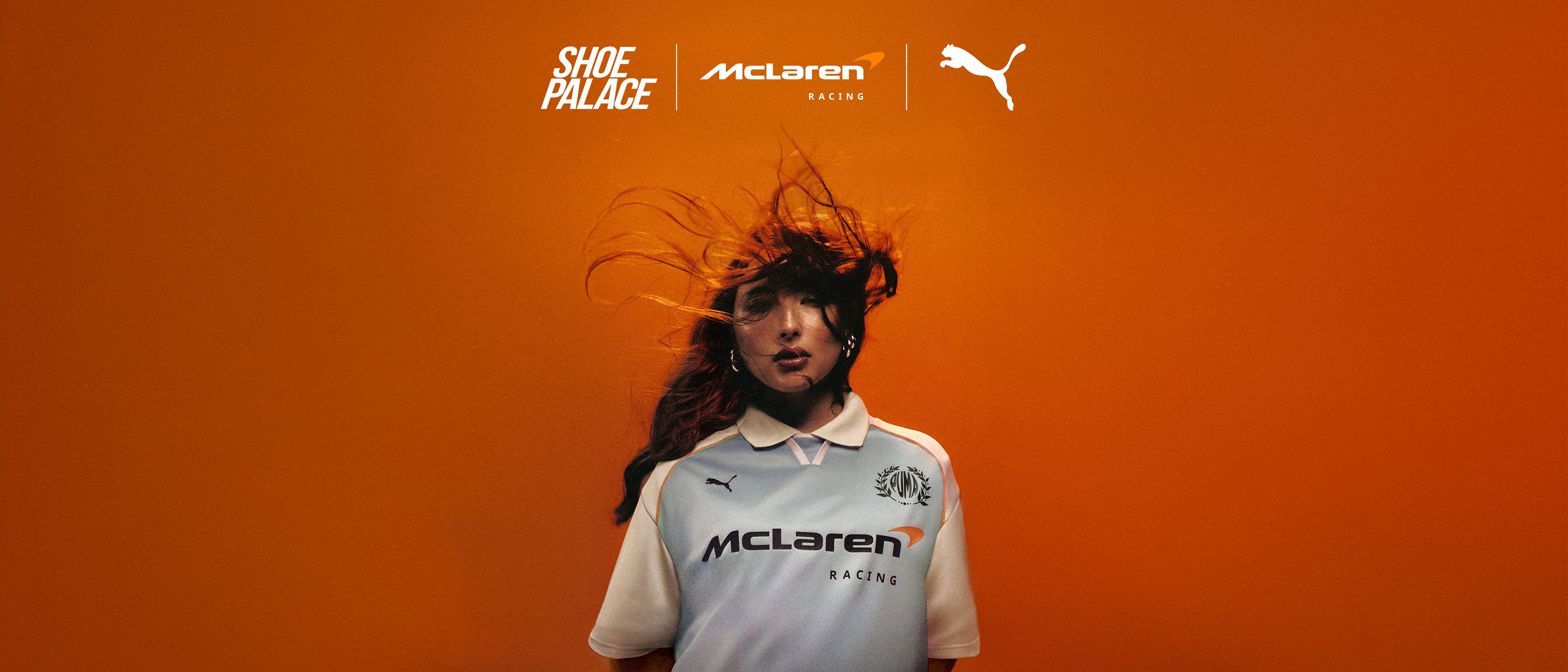 Person wearing a white Puma jersey against an orange background.