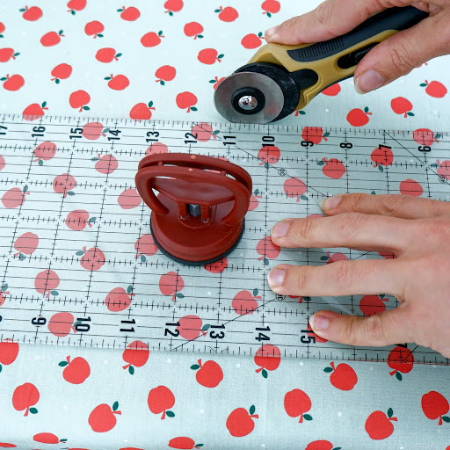 Hand cutting apple fabric with a rotary cutter and an acrylic ruler