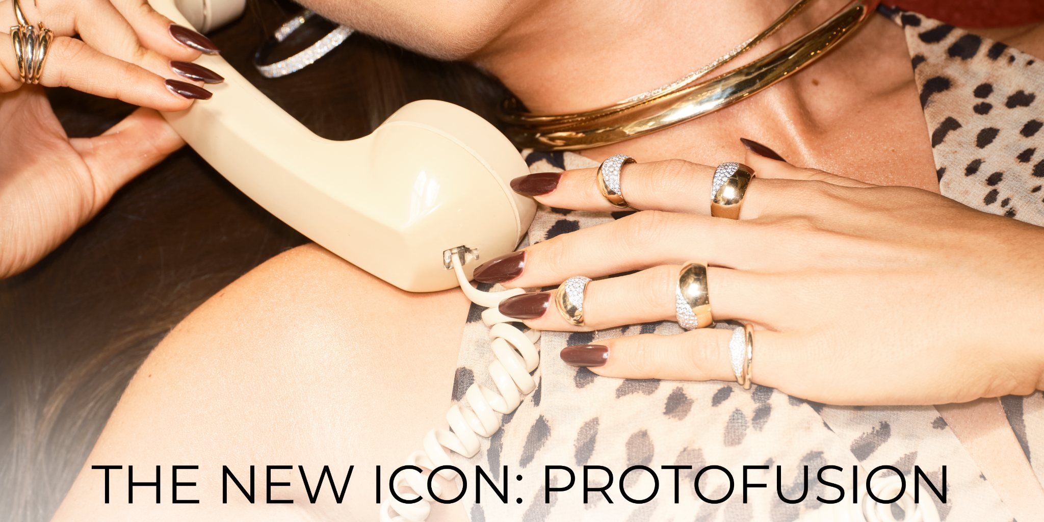 A hand holding a vintage phone with stylish accessories and jewelry.