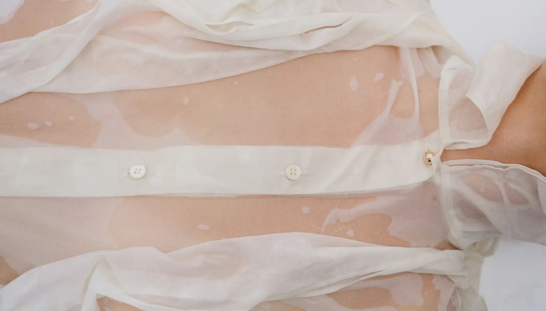 A close-up of a sheer, button-up blouse on a person.