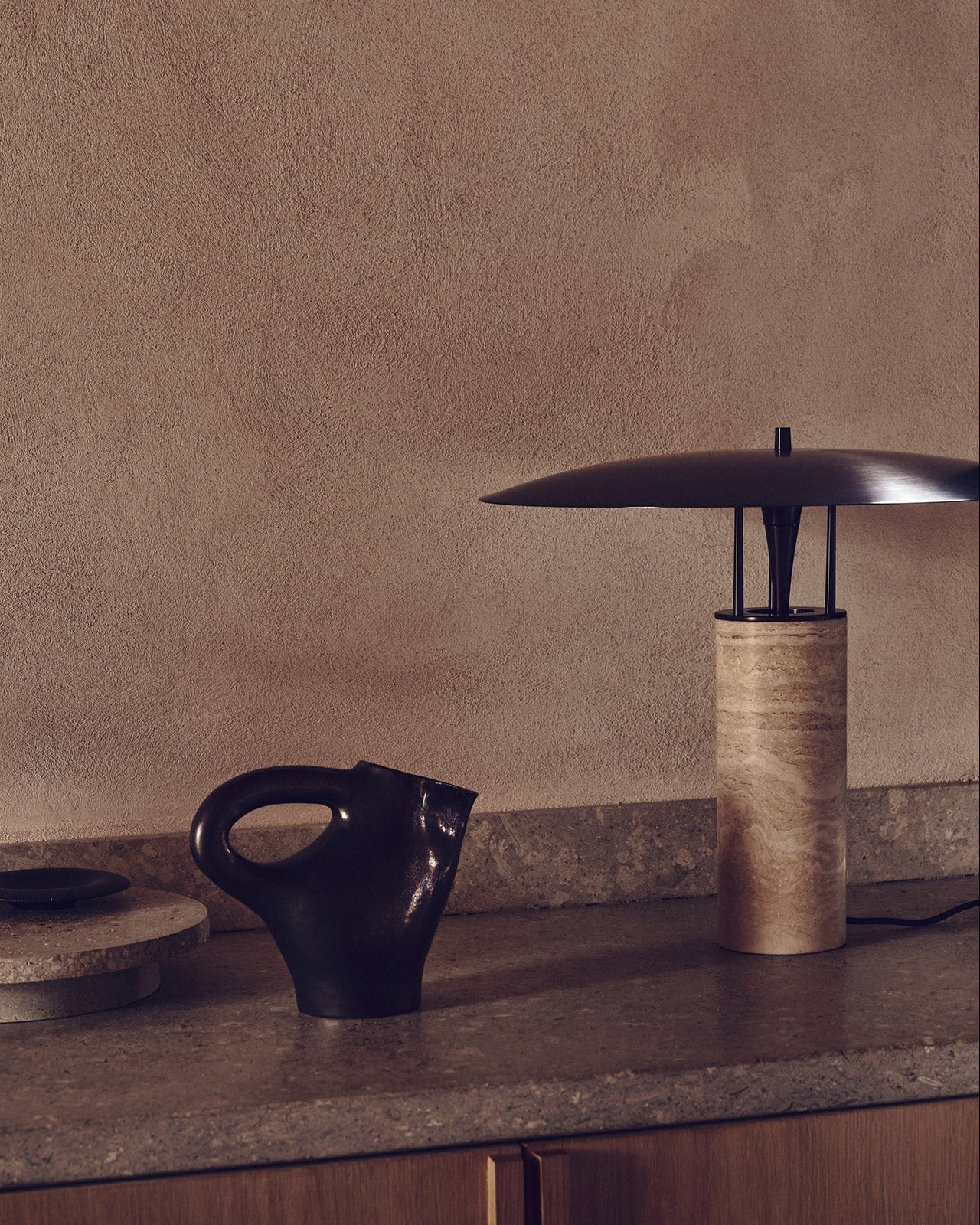 Modern table lamp and black ceramic object on a wooden surface with a neutral background
