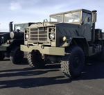 Front three-quarter olive drab M923A2 steel bumper mesh grille round headlights off-road tires asphalt lot Benjamin's Outlaw train horn gallery photo 3