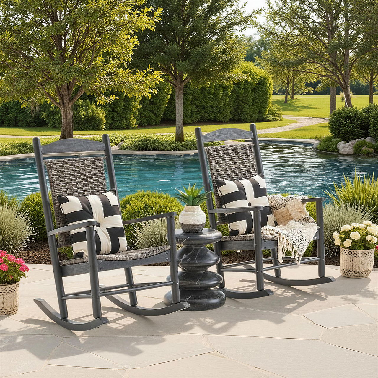Two rocking chairs by a pool, surrounded by greenery and flowers.