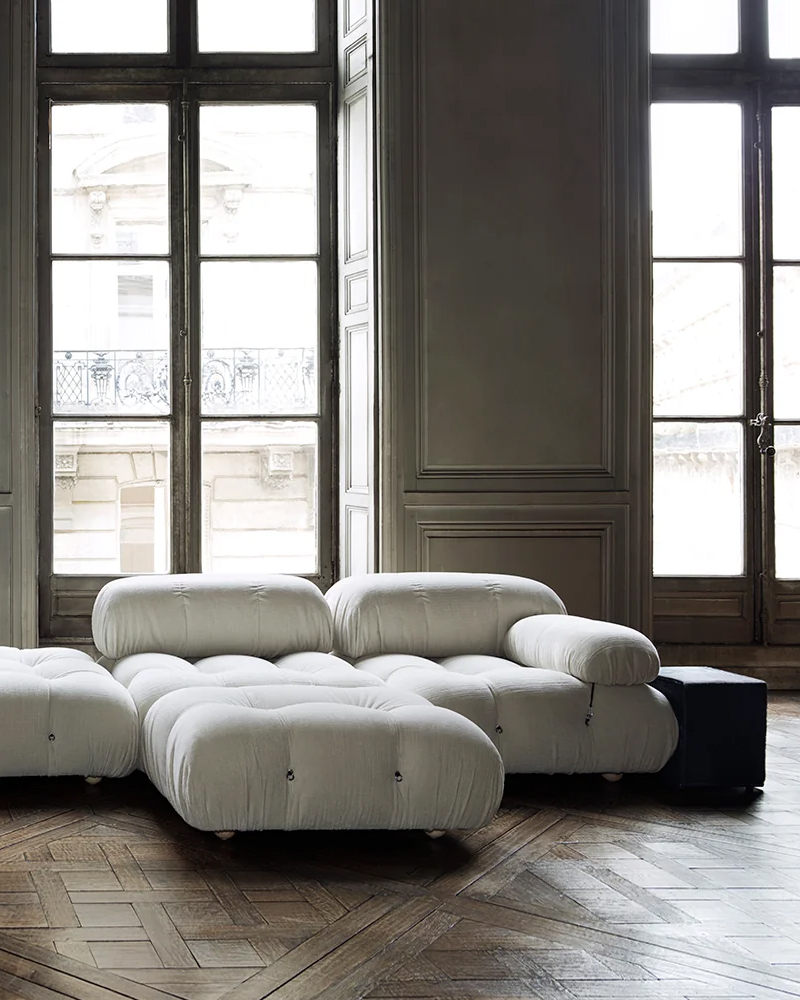 A modern white sectional sofa in a spacious, well-lit room.