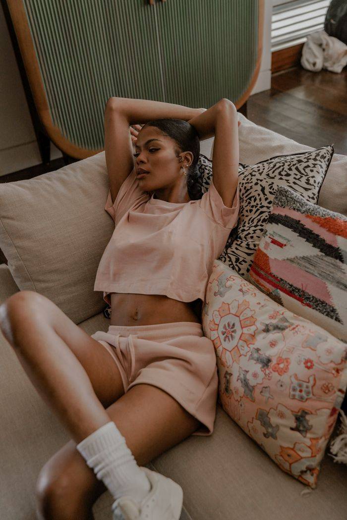 female model wearing pink sacre fleece set laying on couch