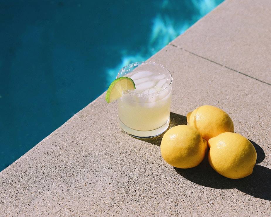 Margarita cocktail at poolside with bunch of lemons