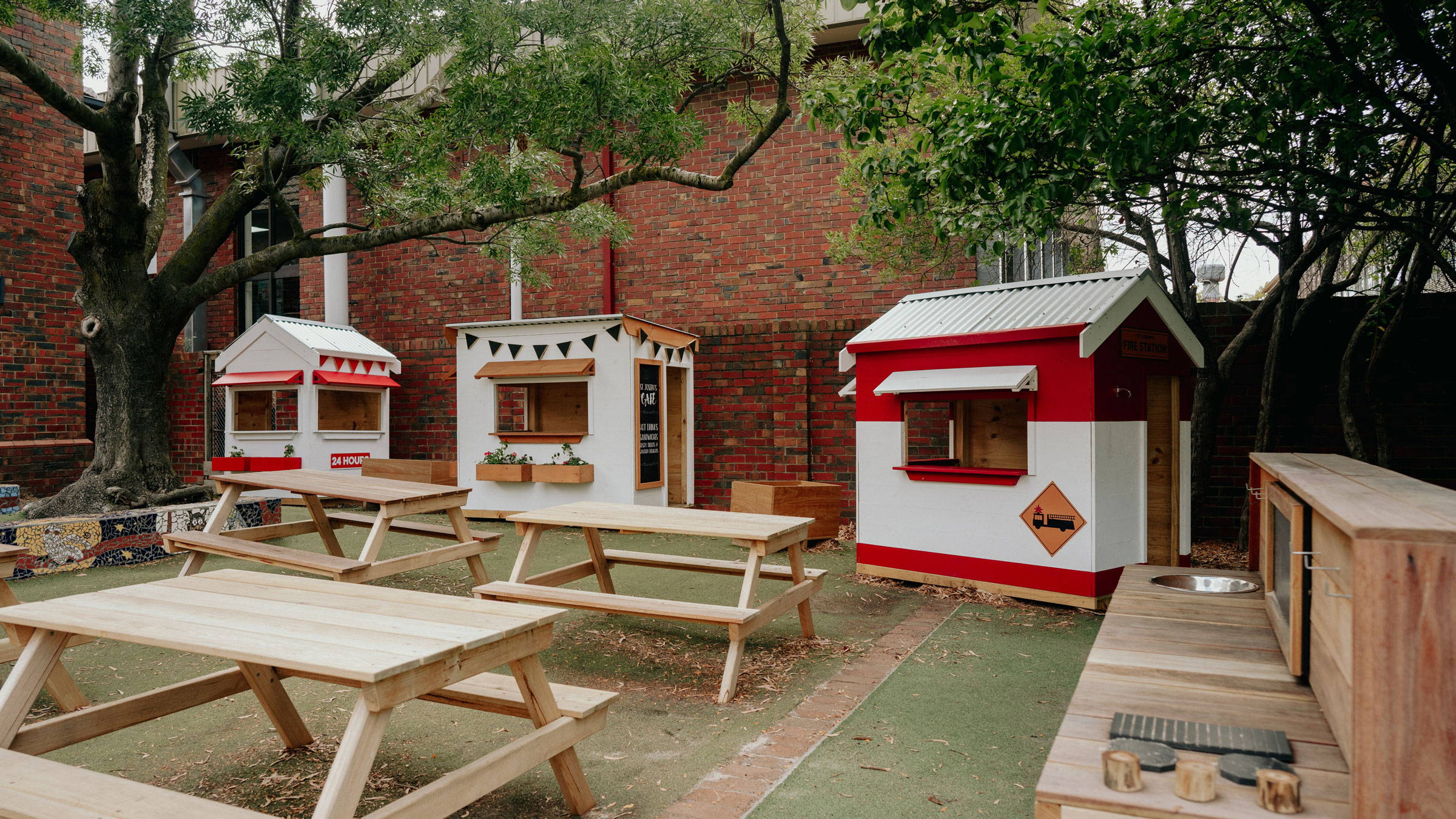 Themed cubby houses with a mud kitchen and picnic tables.