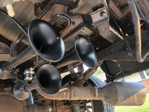 Three black train horns and MBRP exhaust tip installed on the rear undercarriage of a 2006 Ford F250
