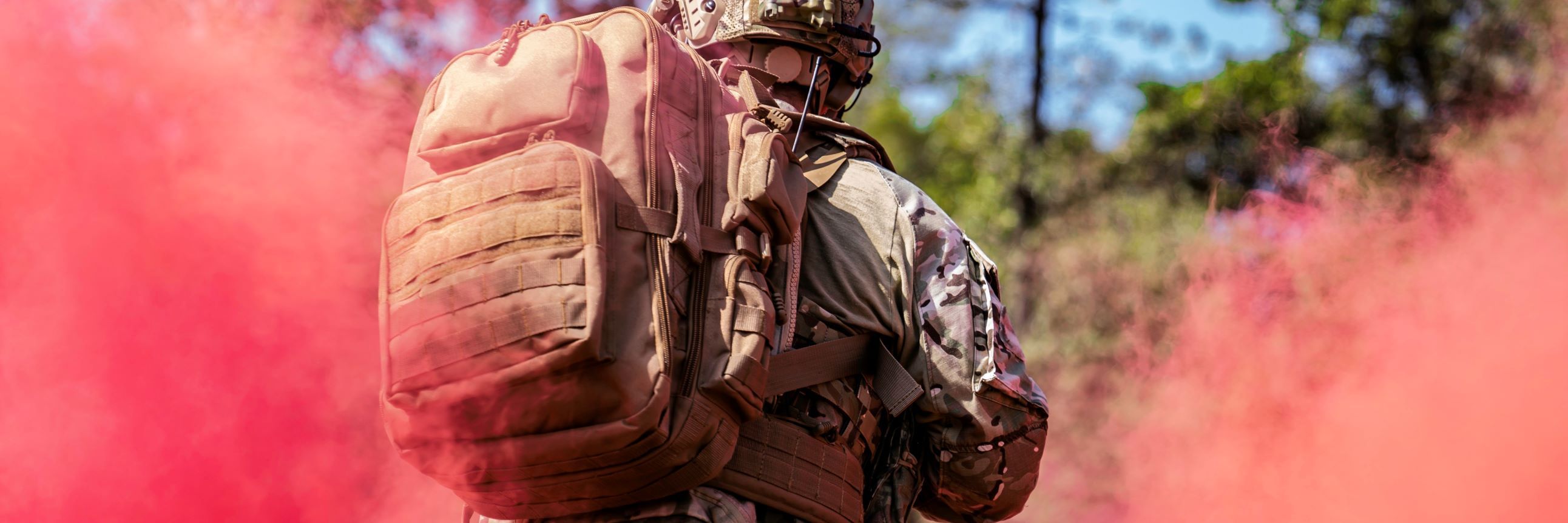 Coyote Brown Brazos Backpack worn outdoors surrounded by red smoke.