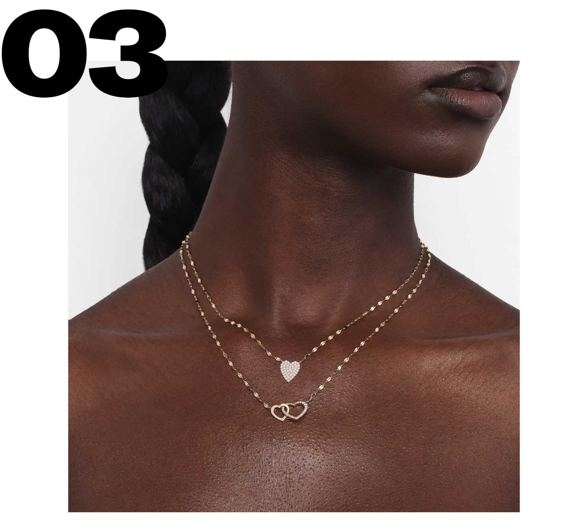 A close-up of a model wearing layered gold necklaces.