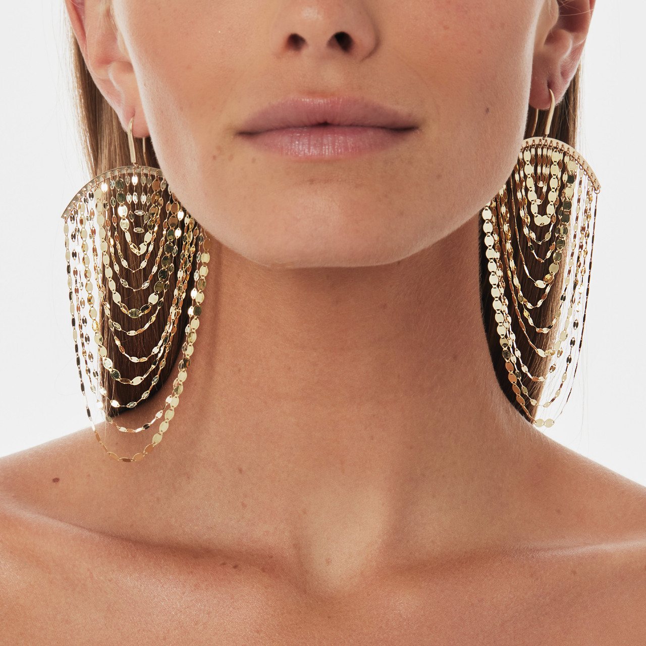 Close-up of a woman wearing large, intricate gold earrings.