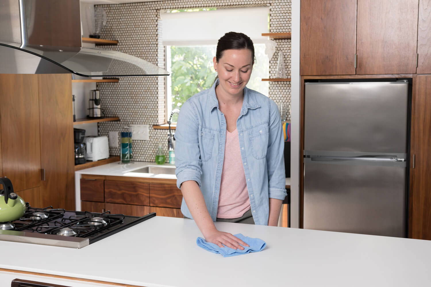woman cleaning kitchen counter with microfiber towel