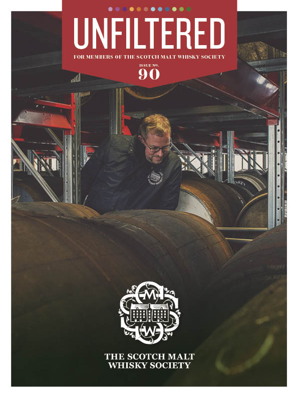 A person inspecting whisky barrels in a distillery setting.