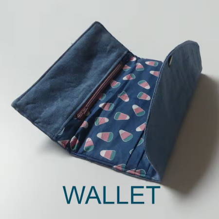 A diy wallet made out of blue fabric and fabric with a print, it has a zipper