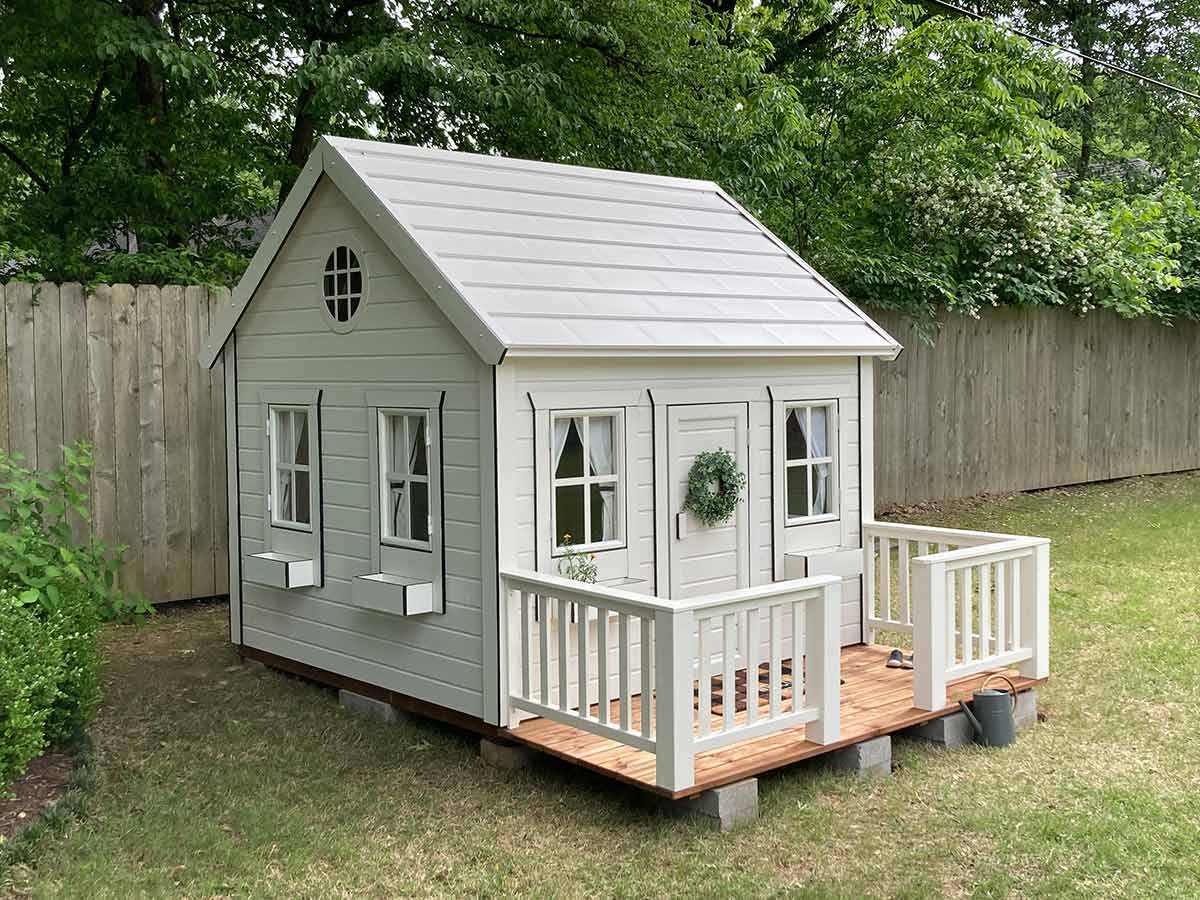  Wooden Playhouse with black trims, round top window, wooden terrace and flower boxes in the garden by WholeWoodPlayhouses