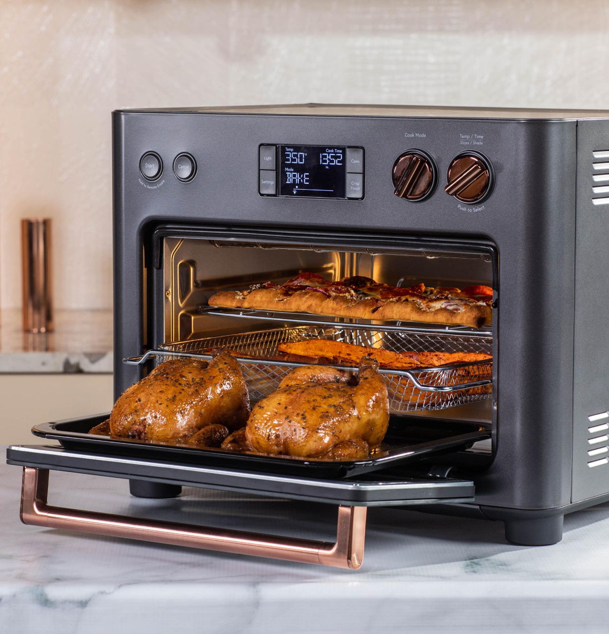 A matte black couture countertop oven with roasted chicken inside.