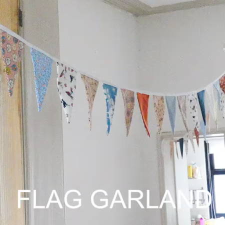 A diy flag garland hanging from the ceiling in a bright room
