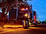 Low-angle front three-quarter black Kenworth semi amber LED bumper lights chrome grille exhaust stacks dusk blue hour Glen's Outlaw train horn kit featured customer install gallery photo 1