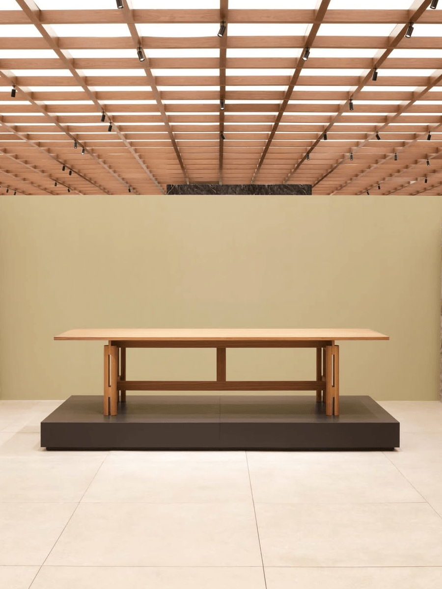 A wooden Abaco DIning table on a platform in a modern interior space.