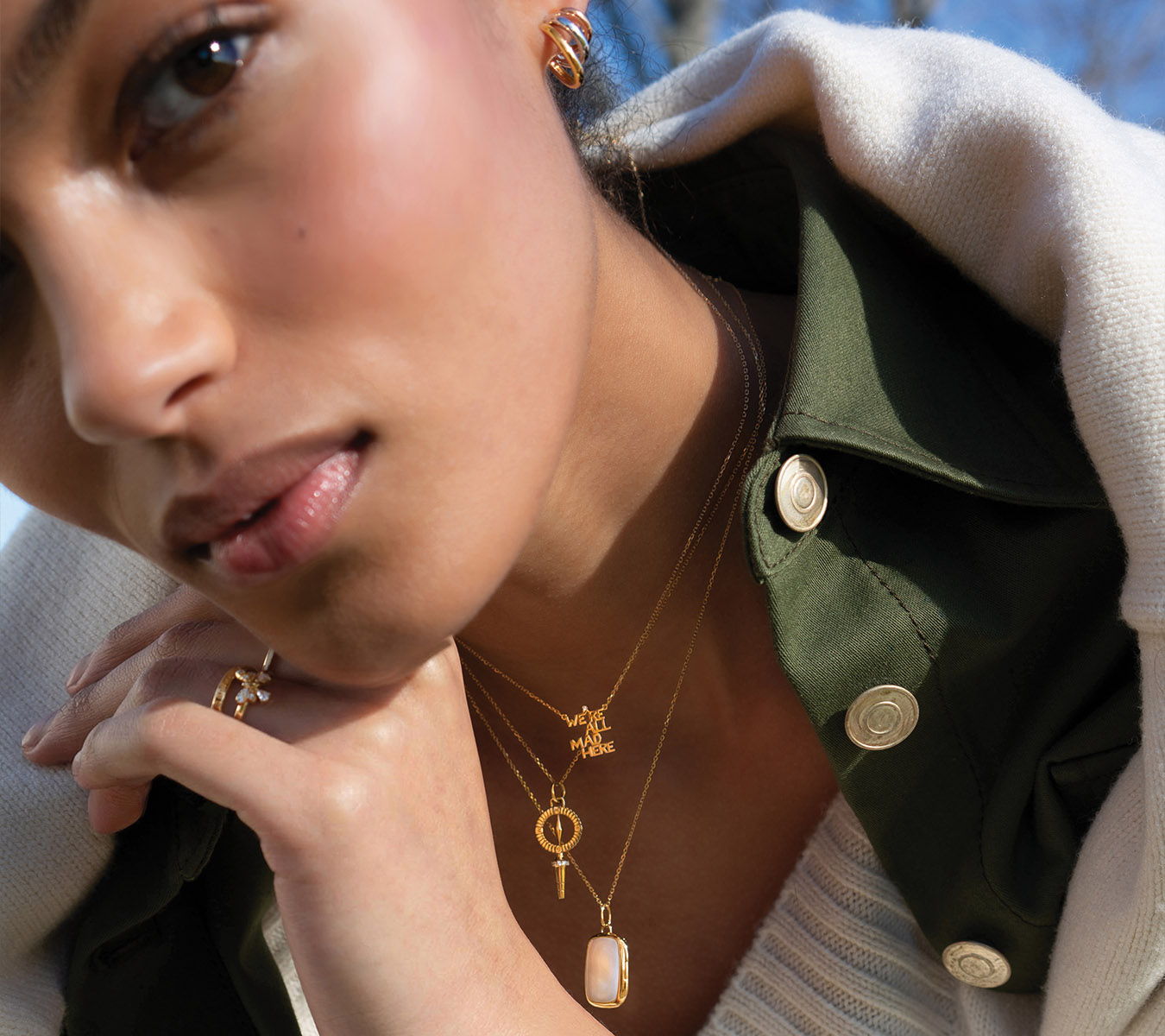 A close-up of a woman wearing layered gold necklaces and earrings.