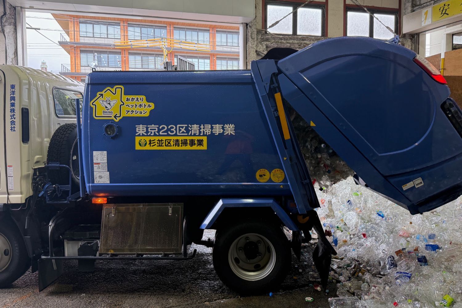 A blue garbage truck unloading waste in a building.