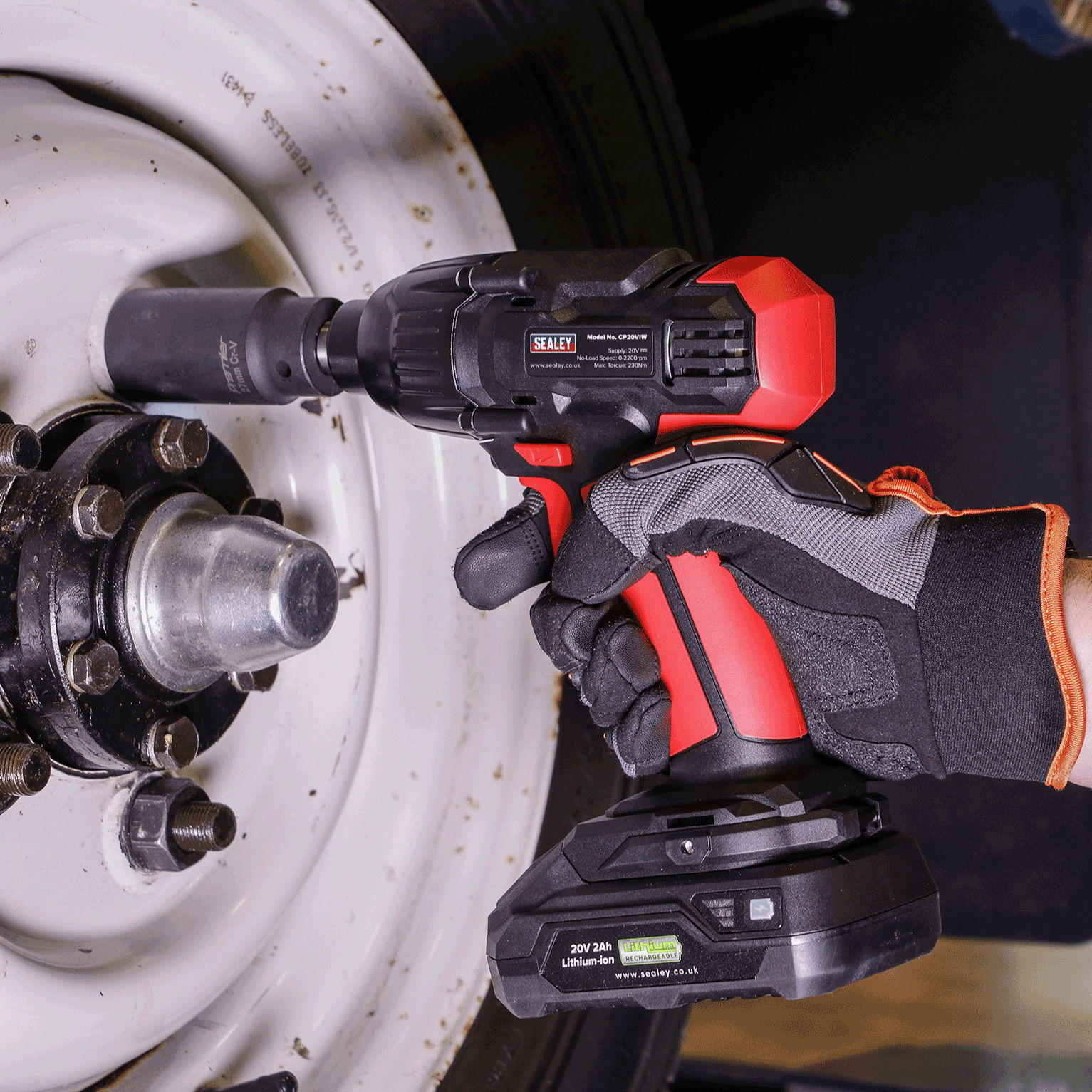 A person using a cordless impact wrench on a vehicle wheel.