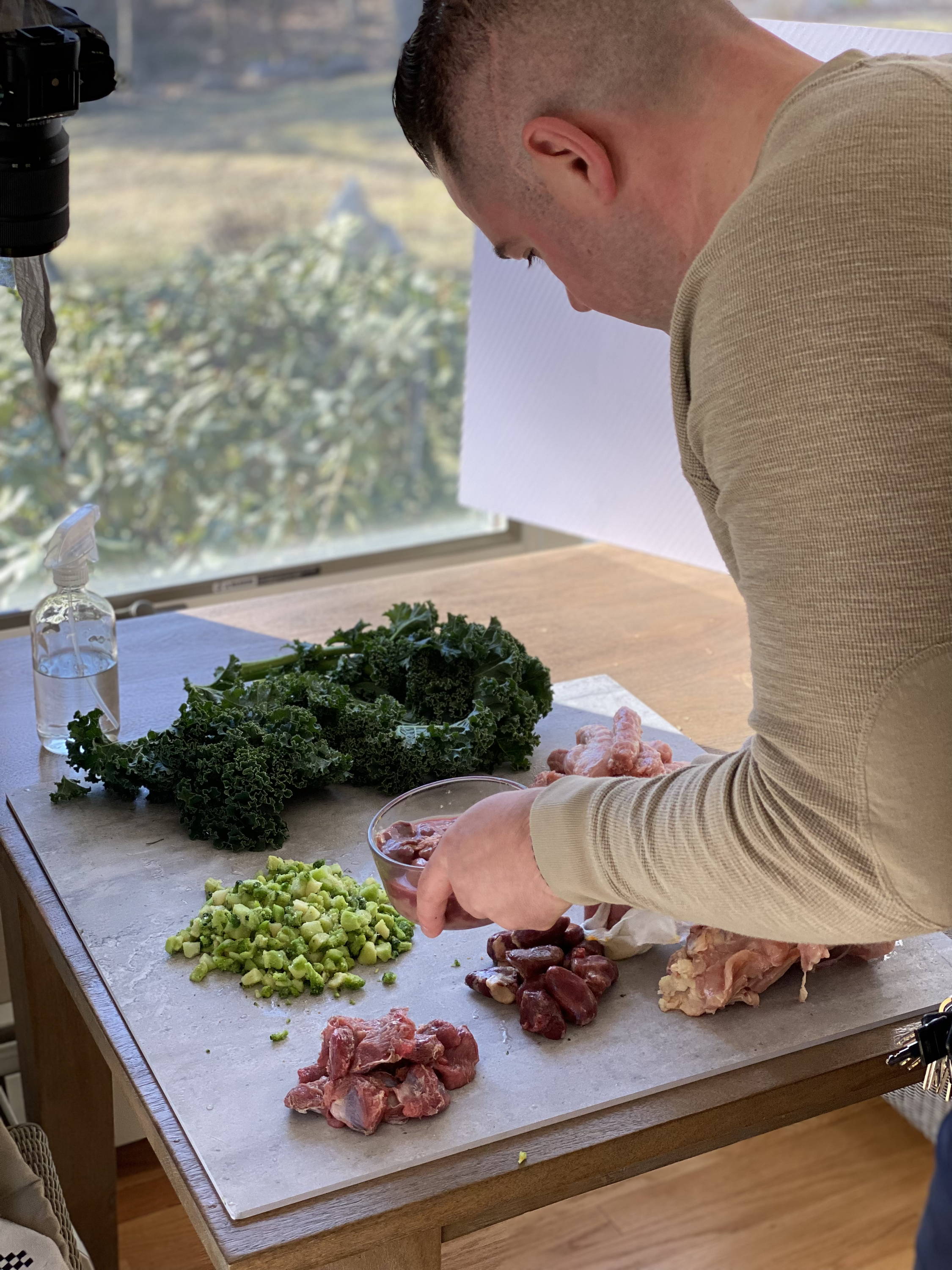Man arranges meat and vegetables on table for photoshoot.