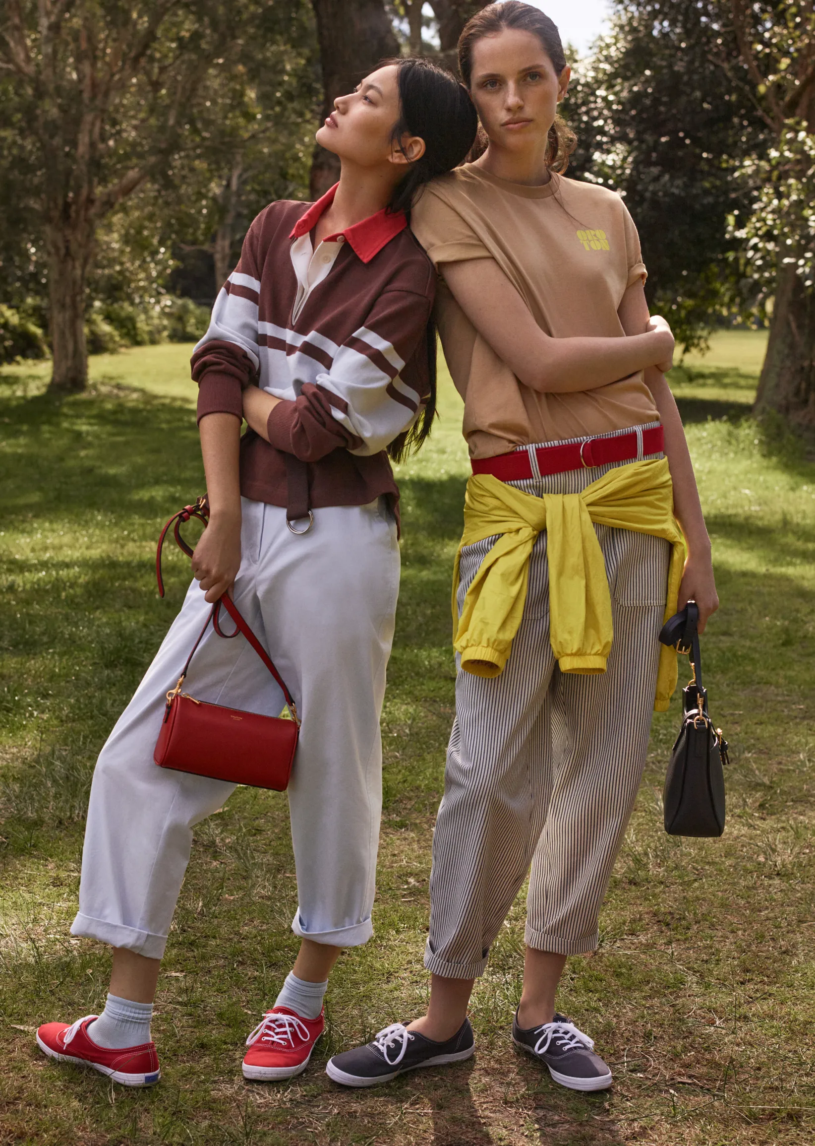 Two women in casual outfits posing outdoors in a park.