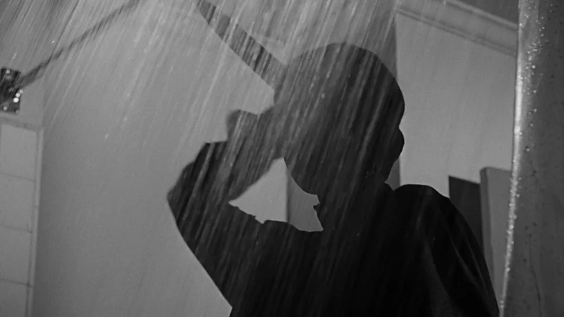 Silhouette of a person in a shower with water cascading down.