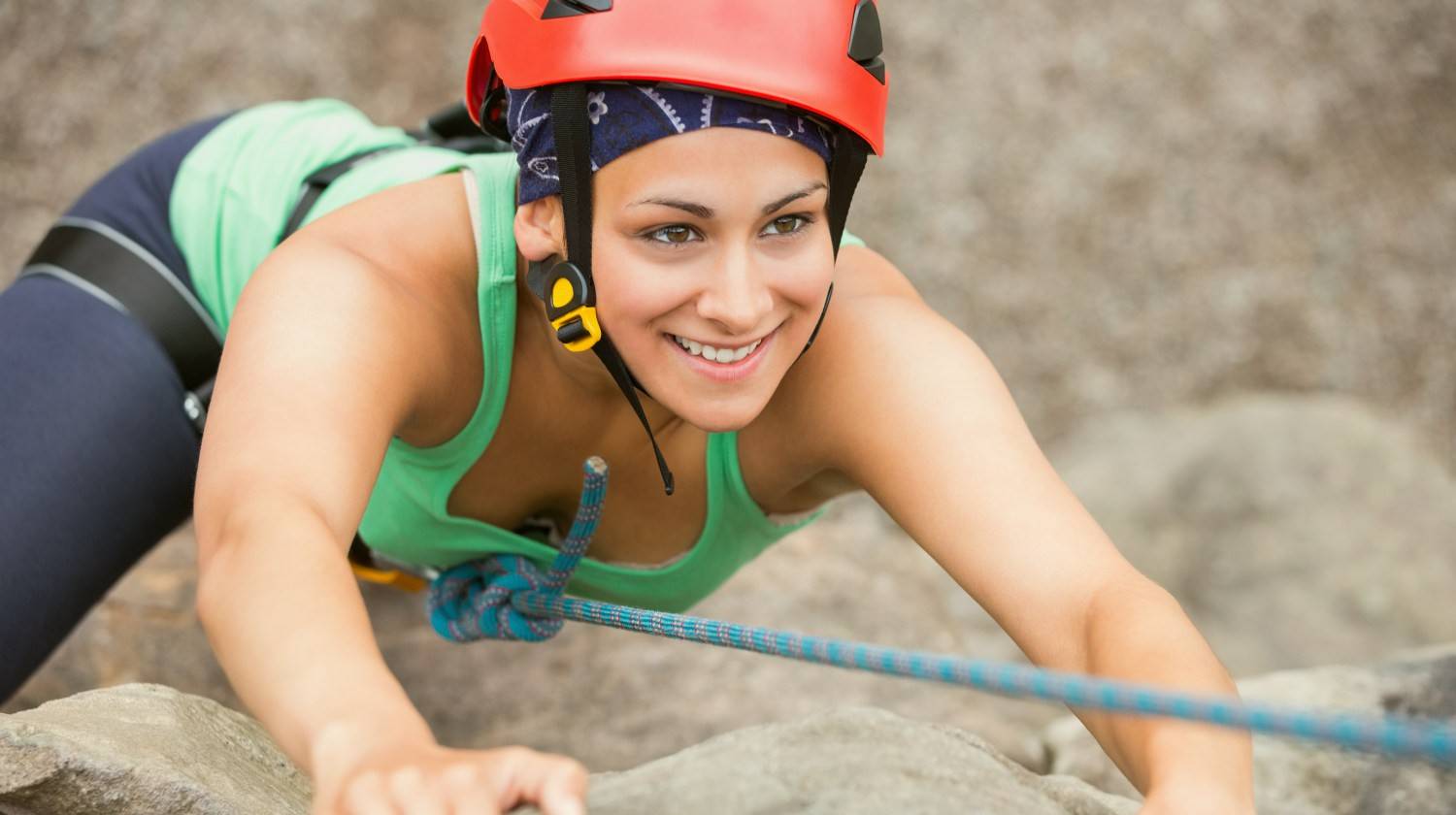 Happy girl climbing rock face wearing red helmet | Rewire Your Implicit Memory for a Happier Life | Featured | perceptual priming