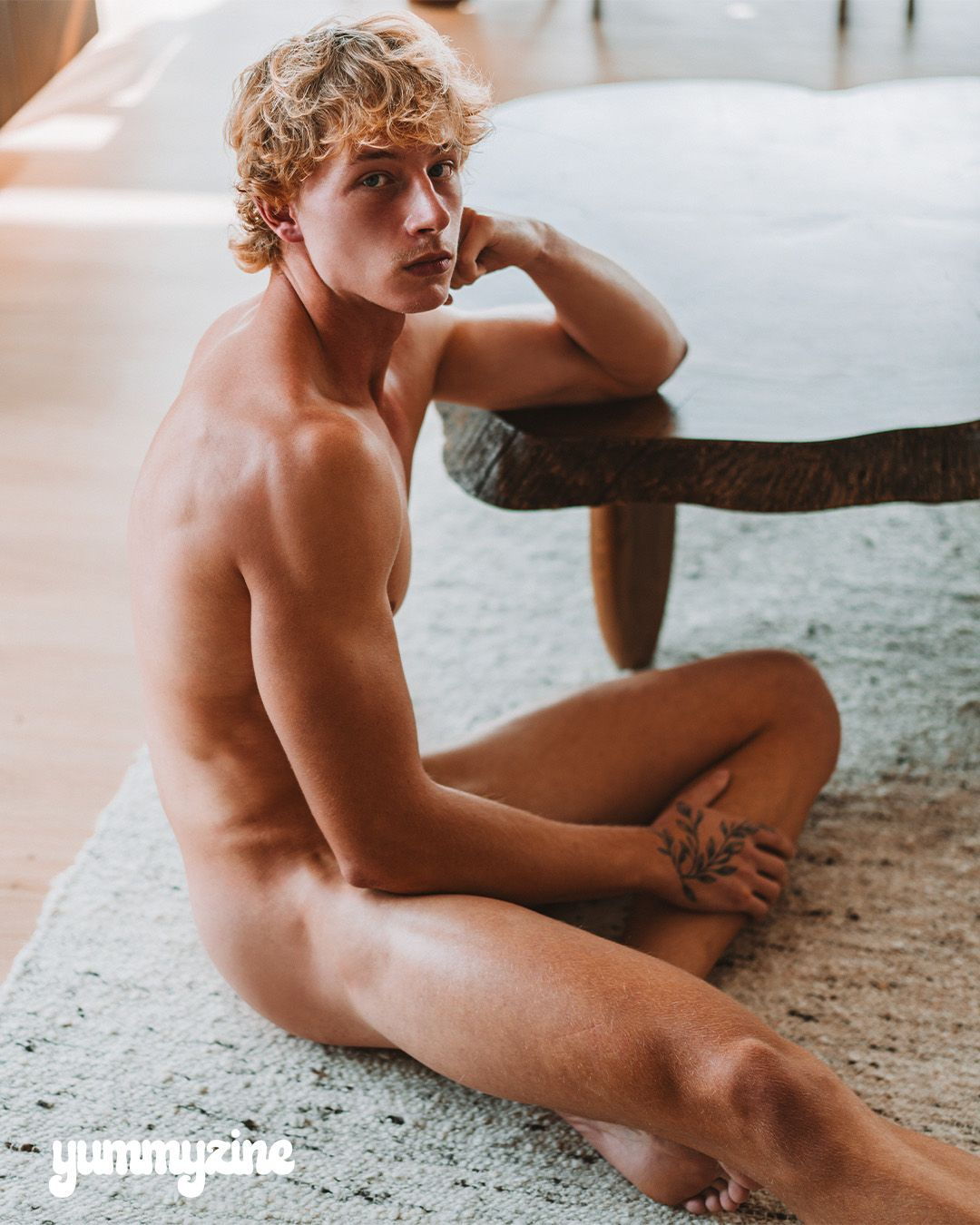 A person sitting on a rug beside a table.