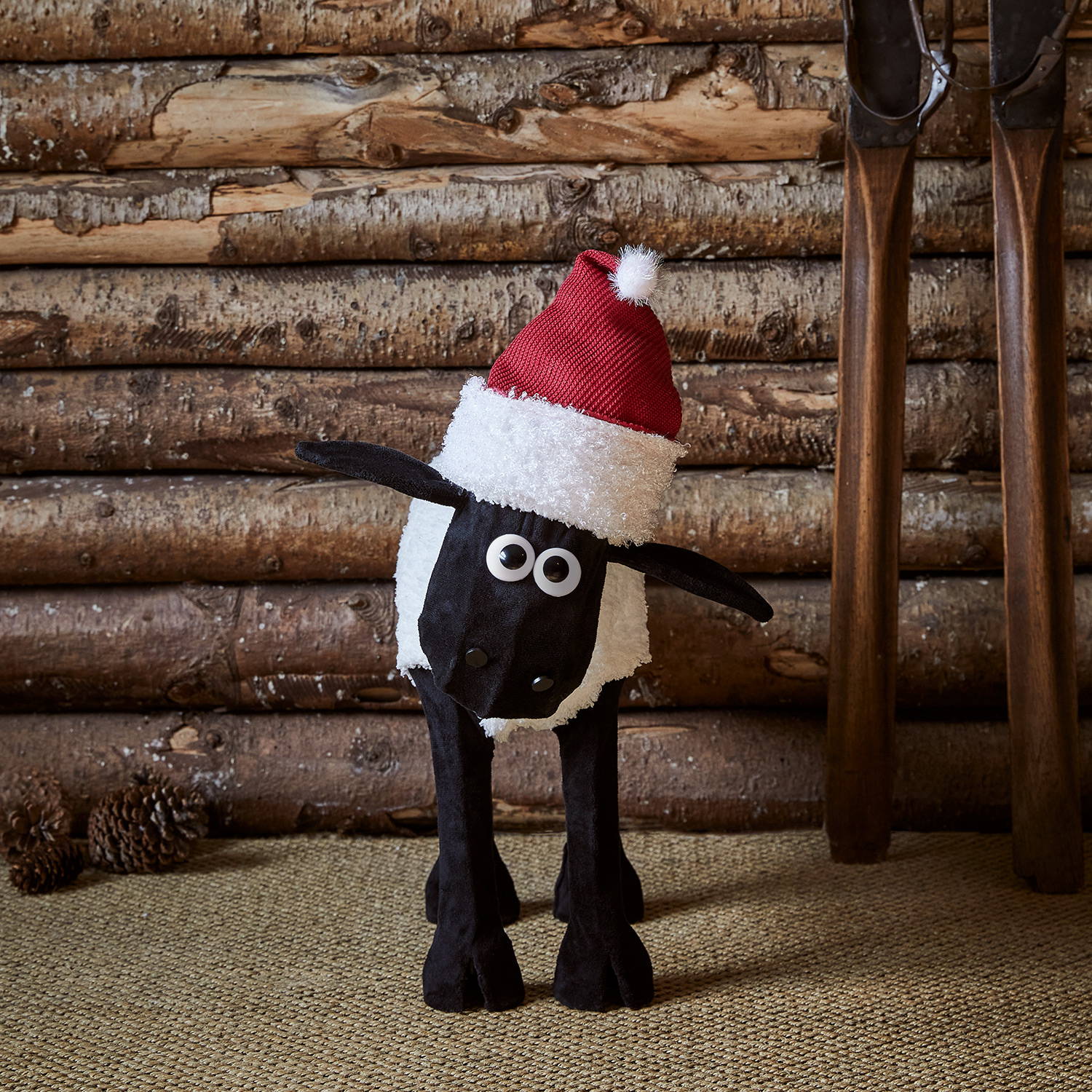 Shaun the sheep mit Weihnachtsmütze steht in einer Hütte
