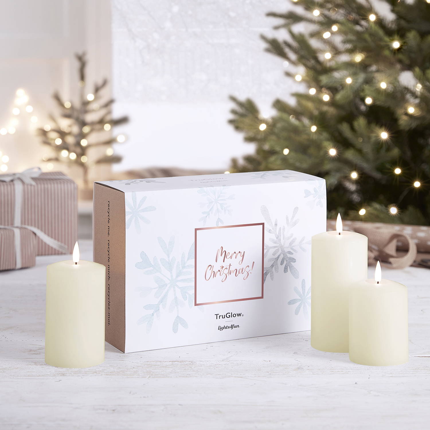 Gift wrapping Christmas sleeve over a TruGlow pillar candle trio box with the ivory LED pillar candles next to it.