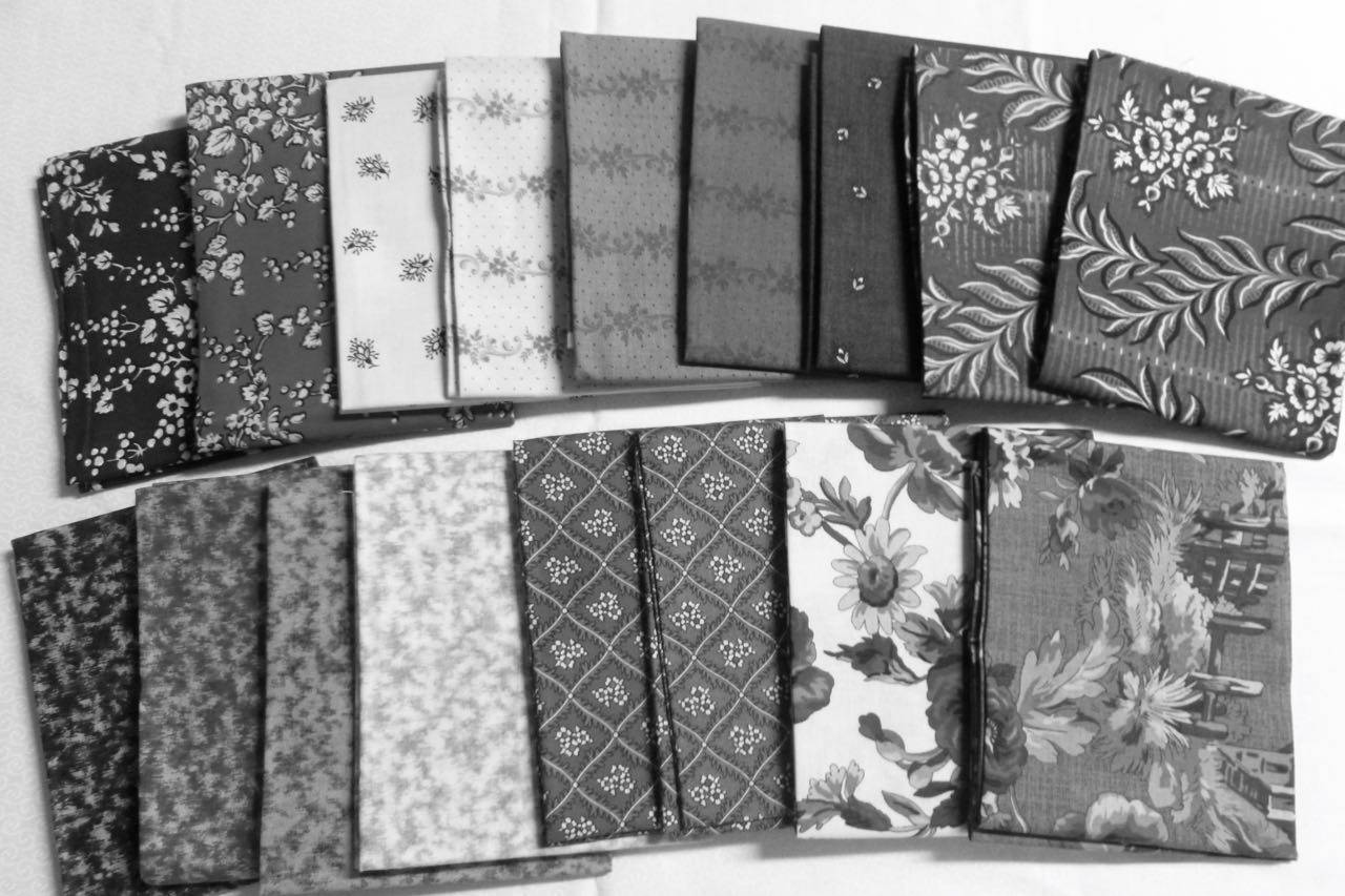 An assorment of quilting fabrics in black and white with light, medium and dark tones