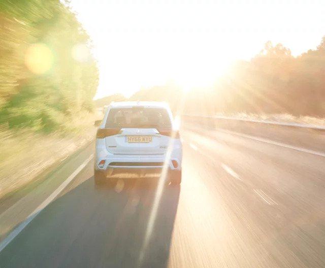 A white car driving on a sunny road.