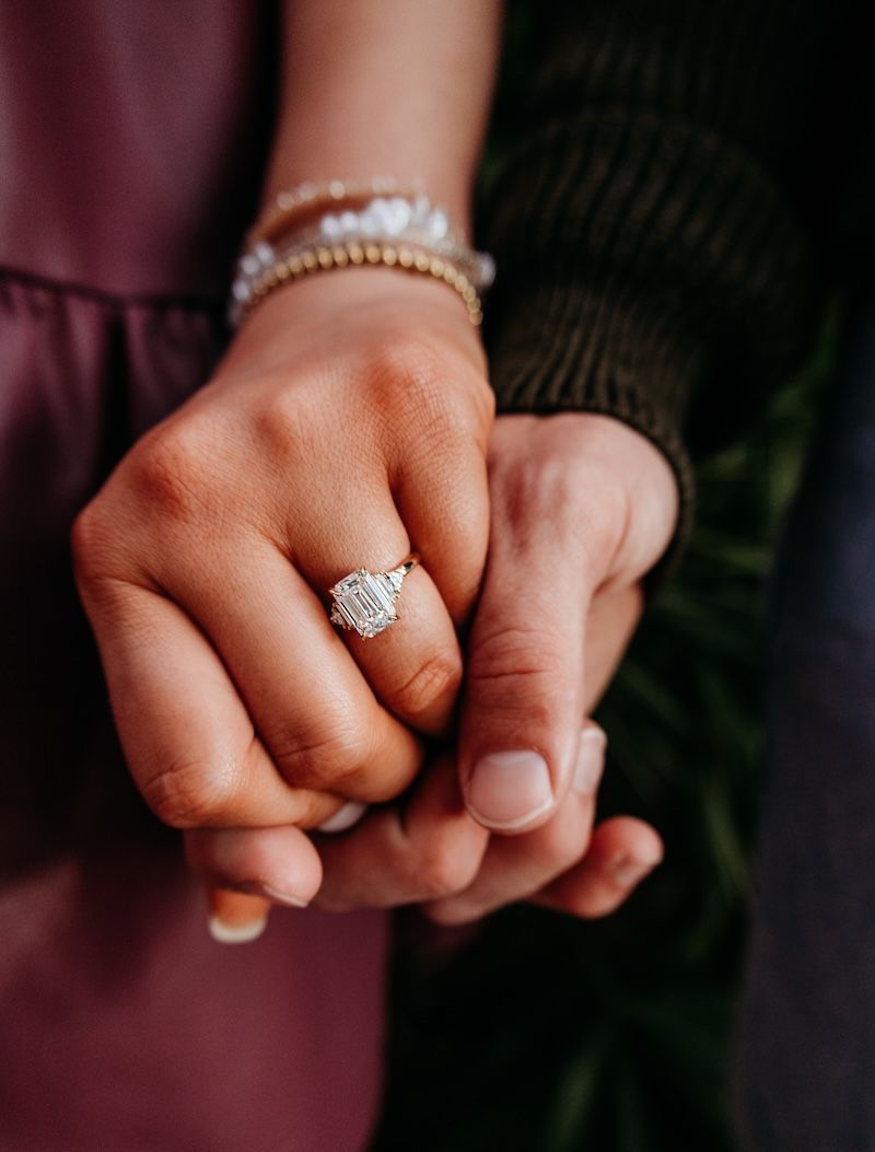 close up of engaged couple and three-stone ring