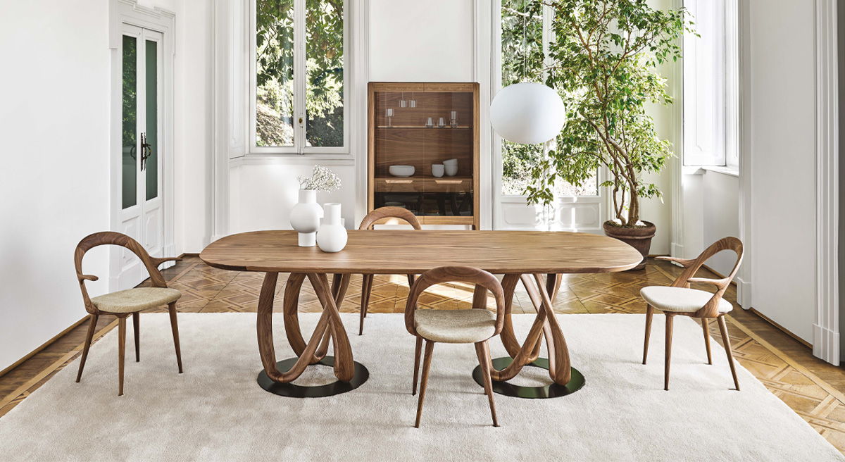 Porada Infinity wooden table and chairs, large windows, and greenery.