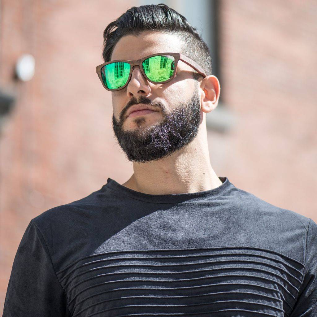 Man wearing two tone sunglasses made with walnut wood and green mirror polarized lenses
