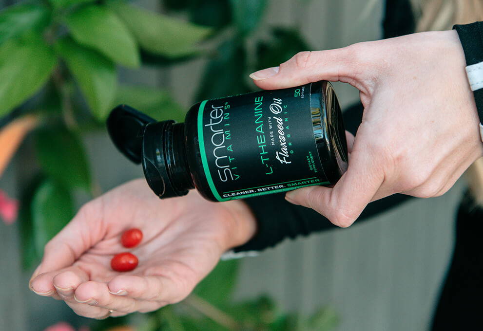 Opened smarter L-Theanine bottle in hand, pouring vitamin into other hand.