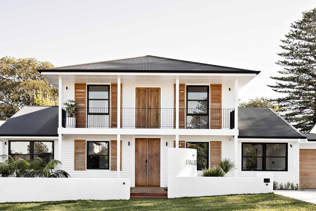 Modern coastal two-story house with wooden accents and landscaped front yard.