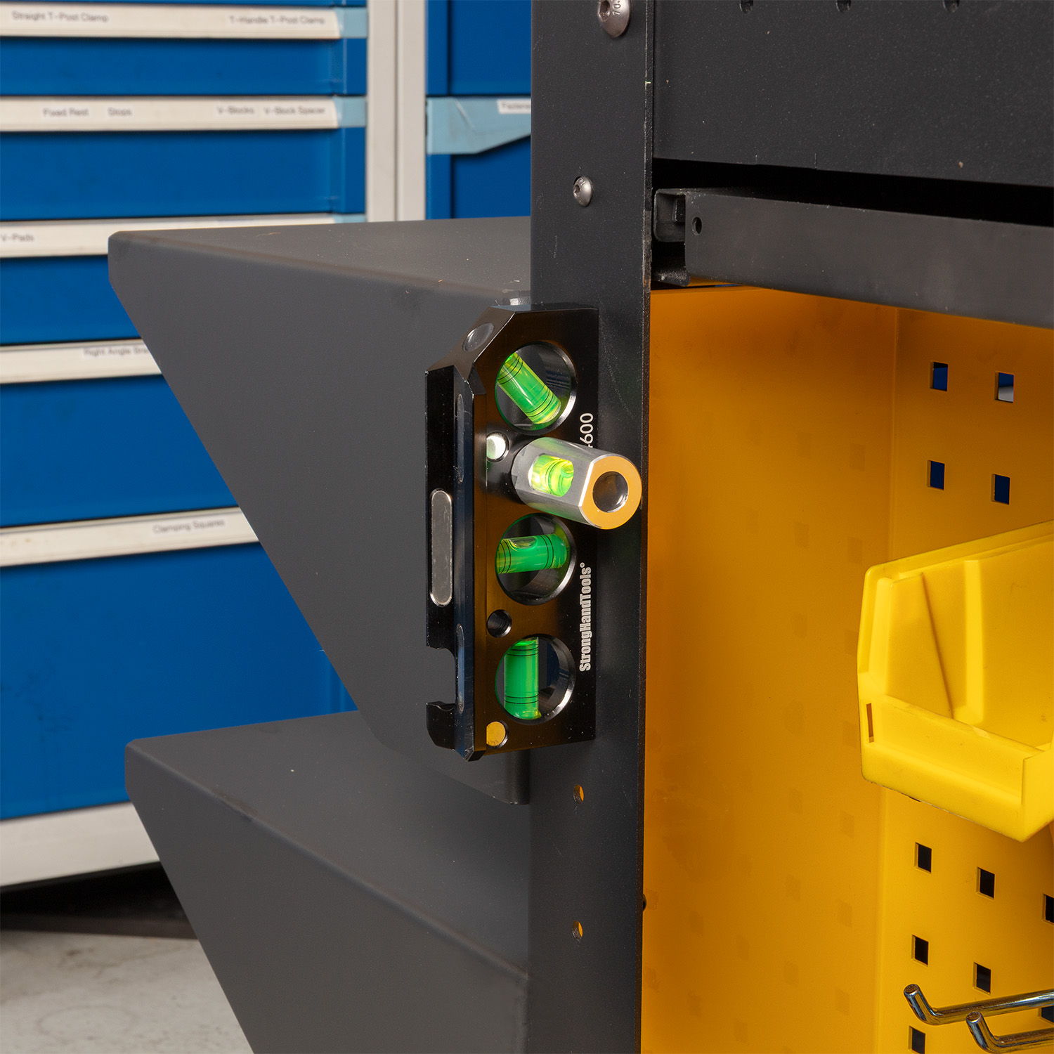 Level tool attached to a black shelving unit in a workshop.