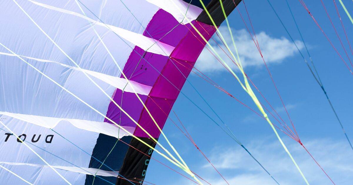 Colorful kite against a blue sky with clouds.