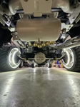 Rear underbody view of white air tank and five gold train horns above white suspension with LED wheel ring lights