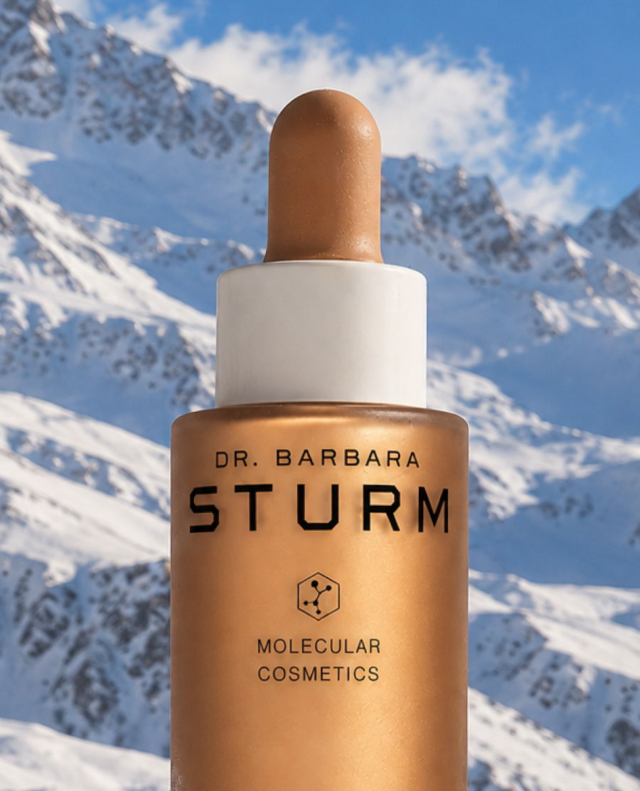Bottle of Dr. Barbara Sturm skincare product against a mountain backdrop.
