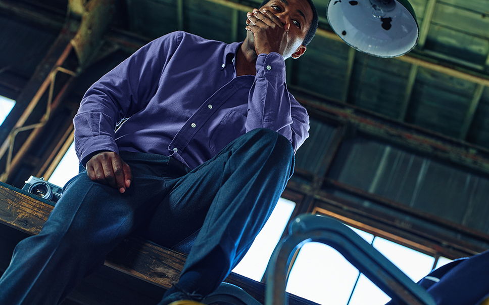 A person sitting thoughtfully in a dimly lit industrial space.