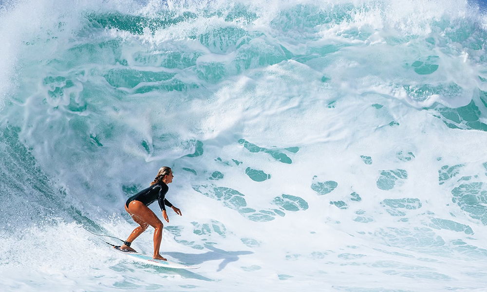 Une surfeuse ride une grosse vague dans l'océan.