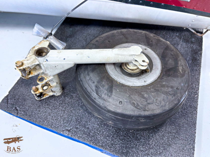 Aircraft landing gear assembly with wheel on textured surface.