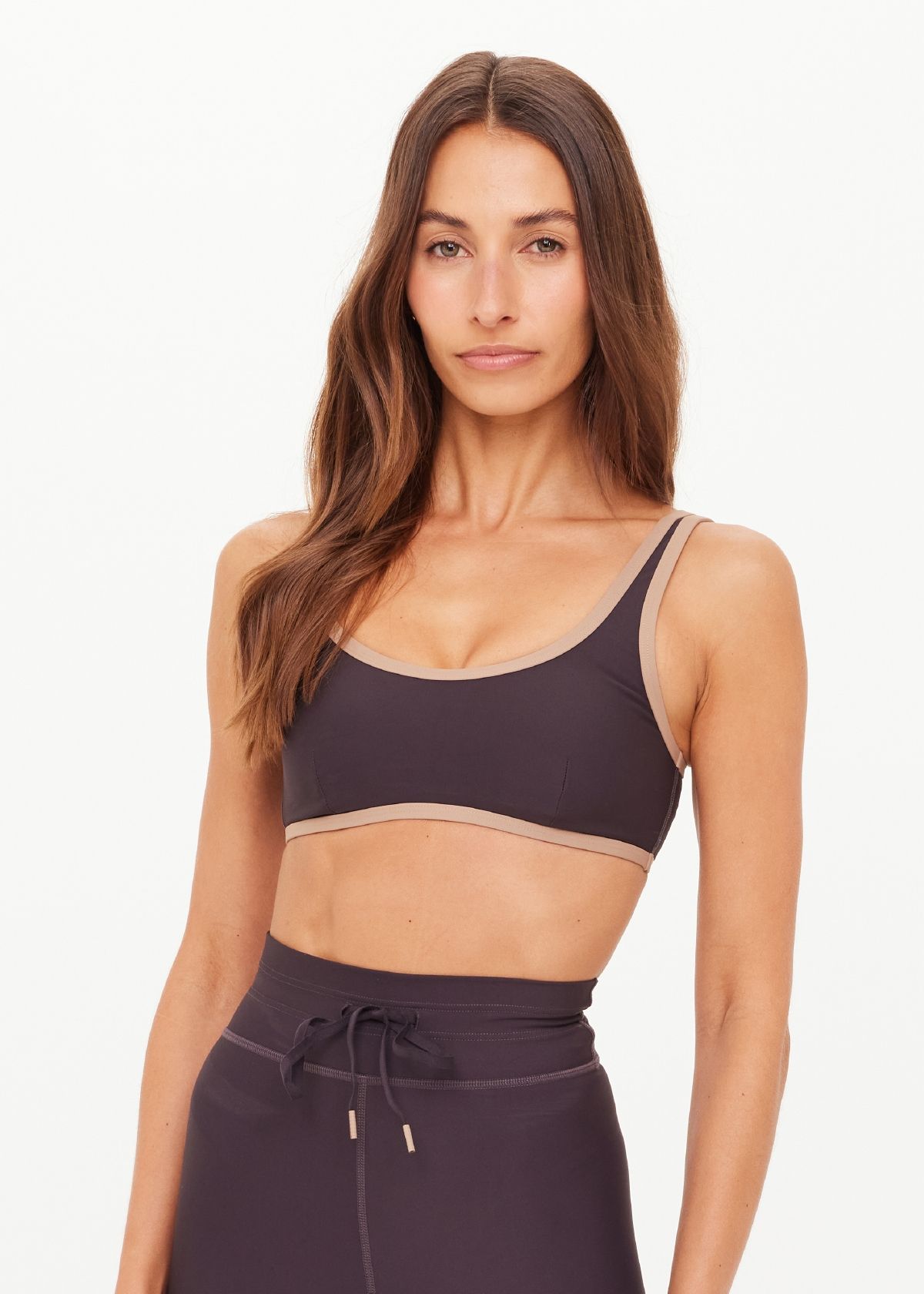 Woman wearing a dark sports bra and matching pants, posing confidently.