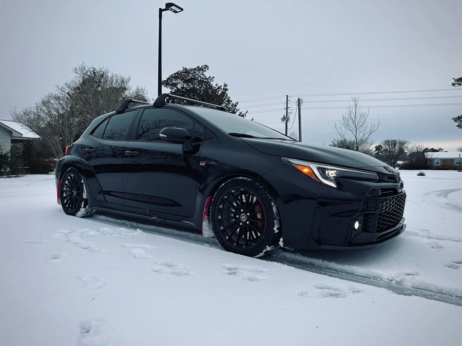 Black 2024 Toyota GR Corolla in snow front three-quarter roof rack and red mud flaps Sniper electric horn featured customer install gallery photo 1